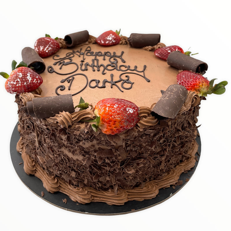 This chocolatey cake is iced in chocolate mousse, rolled in chocolate flakes and has strawberries and chocolate curls on its chocolate mousse borders!